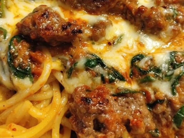 Creamy Cajun sausage spaghetti in a white bowl with melted mozzarella and spinach.