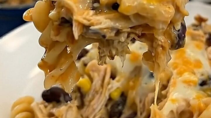 A cheesy bite of fiesta chicken casserole lifted on a fork, showing long glossy melted cheese strings.