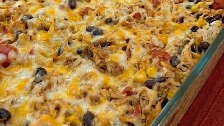 A spatula scooping a portion of cheesy chicken burrito casserole showing an epic melted cheese pull.