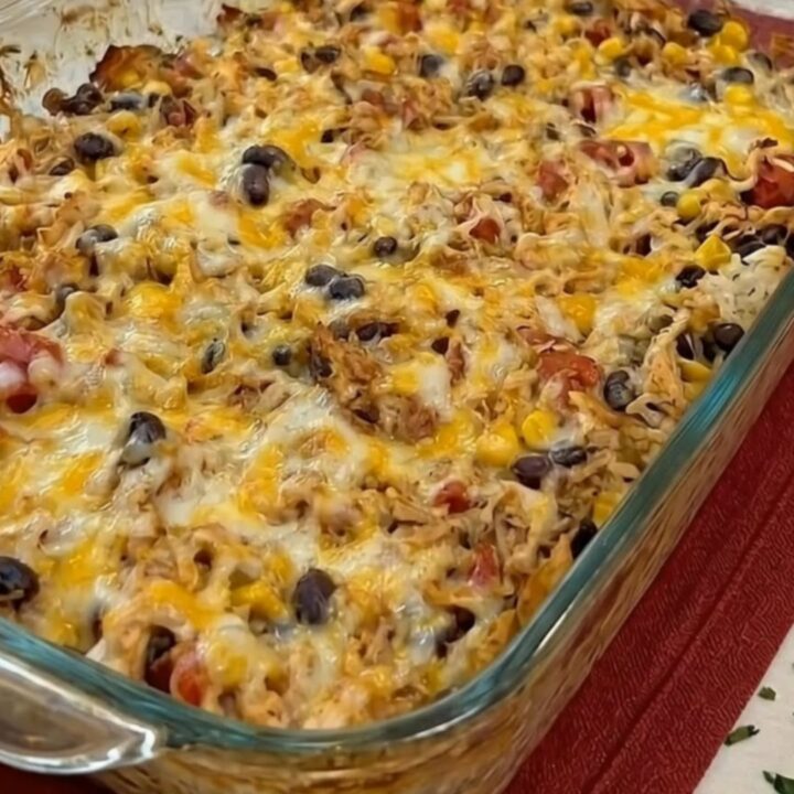 A spatula scooping a portion of cheesy chicken burrito casserole showing an epic melted cheese pull.