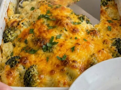 A close-up of a creamy chicken and broccoli casserole in a white dish with a golden melted cheese crust.