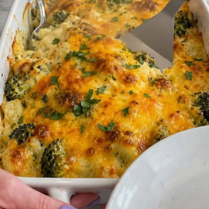 A close-up of a creamy chicken and broccoli casserole in a white dish with a golden melted cheese crust.