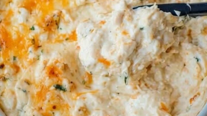 Plat de dip chaud au crabe et cheddar doré, servi avec des crackers sur une planche en bois.