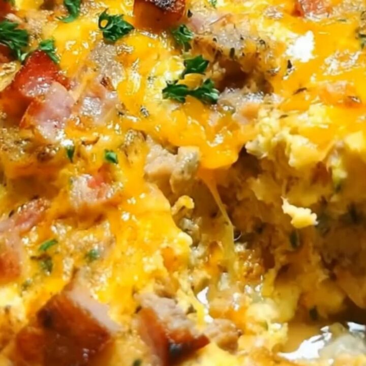 A golden-baked crock pot breakfast casserole with melted cheddar cheese, diced ham, and fresh parsley garnish.