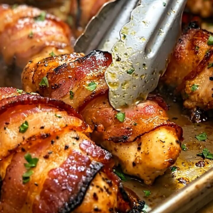 Sizzling crispy bacon-wrapped beef shanks roasted golden brown on a sheet pan.