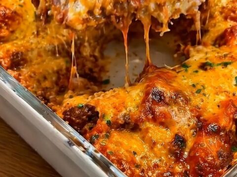 A steaming slice of smoked beef enchilada casserole being lifted with a metal spatula, showing stretchy cheese.