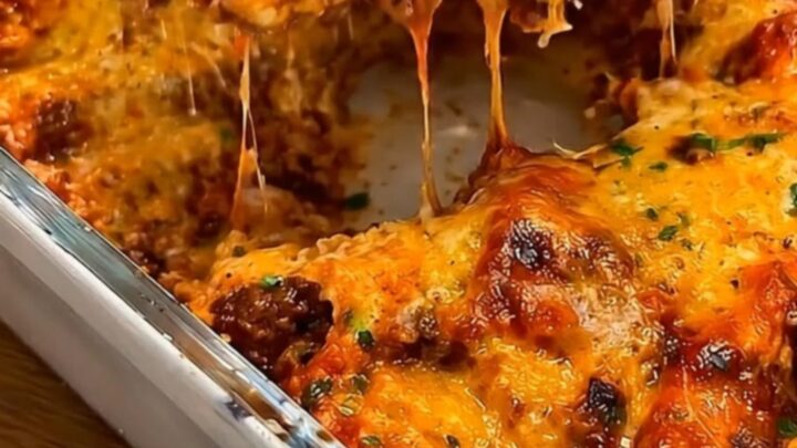 A steaming slice of smoked beef enchilada casserole being lifted with a metal spatula, showing stretchy cheese.