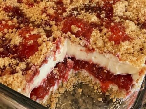 A close-up of a warm strawberry cheesecake dump cake with a golden buttery crust and visible layers of fruit.