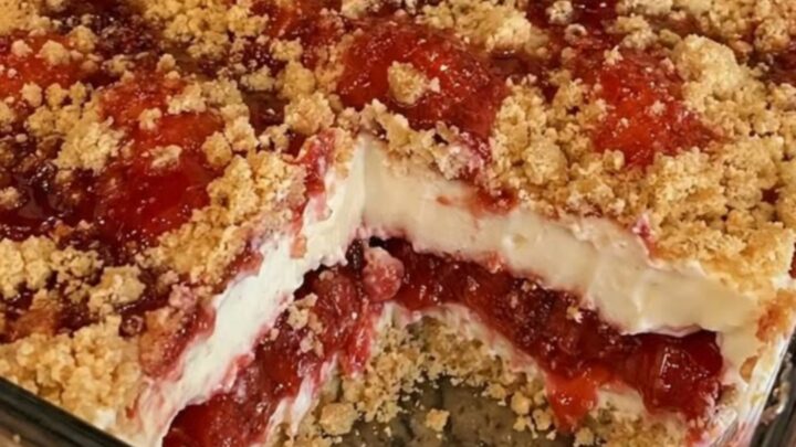 A close-up of a warm strawberry cheesecake dump cake with a golden buttery crust and visible layers of fruit.