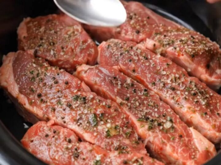A close-up shot of tender, juicy slow-cooked garlic butter steak strips garnished with fresh herbs.