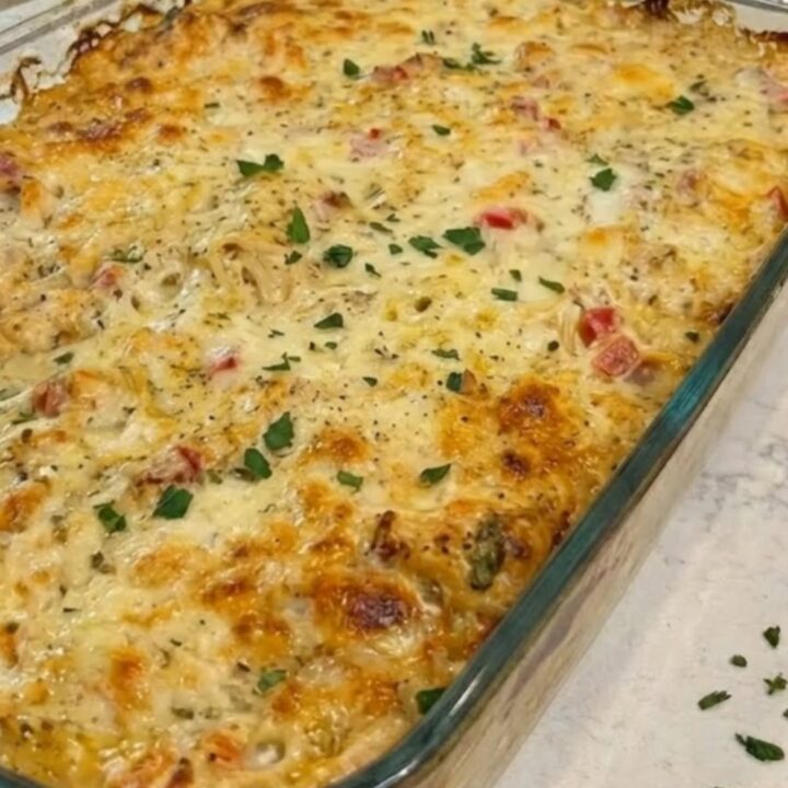 A steaming scoop of cheesy Texas chicken spaghetti being lifted from a baking dish with an epic cheese pull.