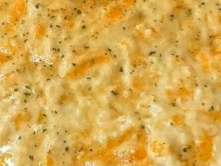 Sloppy Joe casserole in a baking dish with a golden, bubbling cheddar biscuit crust topped with herb flecks.
