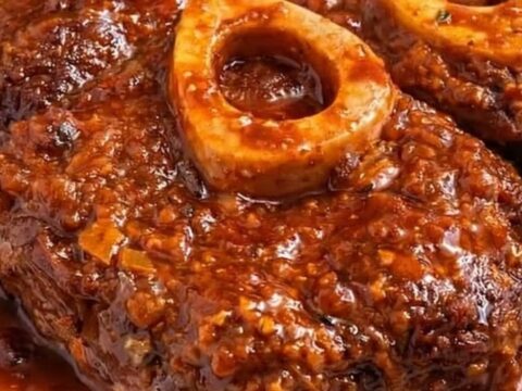 Classic braised osso buco with roasted potatoes on a white plate.