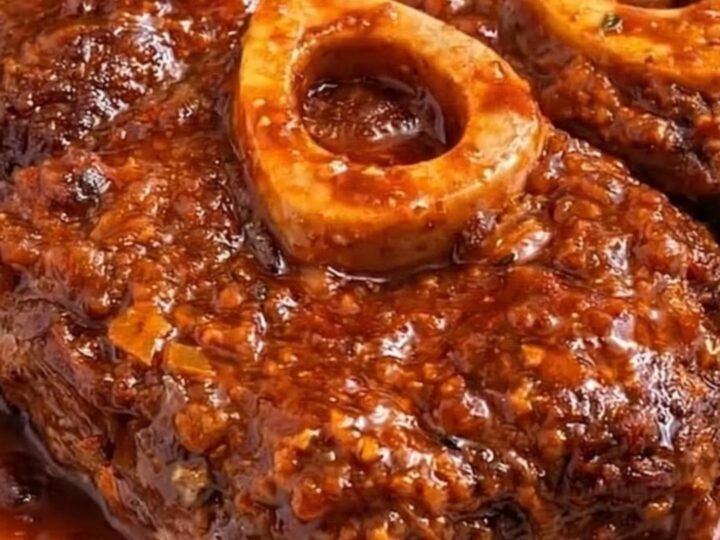 Classic braised osso buco with roasted potatoes on a white plate.