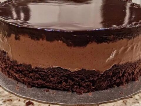 Gâteau mousse au chocolat en couches avec glaçage miroir brillant sur un plateau argenté.