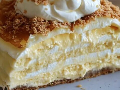 Une part de gâteau de crêpes en couches régulières avec de la crème et des éclats de biscuits sur une assiette.
