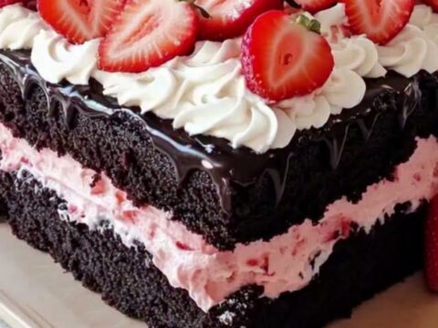 Gâteau carré au chocolat avec une couche de crème rose à la fraise et des décorations en chantilly sur le dessus.