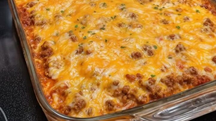 A close-up of a spatula scooping out a serving of cheesy Mexican casserole with long cheese pulls.