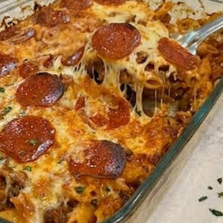 A warm, steaming pepperoni pizza pasta casserole in a clear glass baking dish with bubbly cheese.
