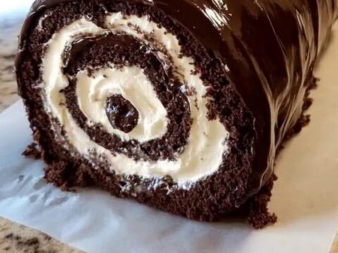 Un beau roulé au chocolat nappé d'une ganache brillante et décoré de chantilly.