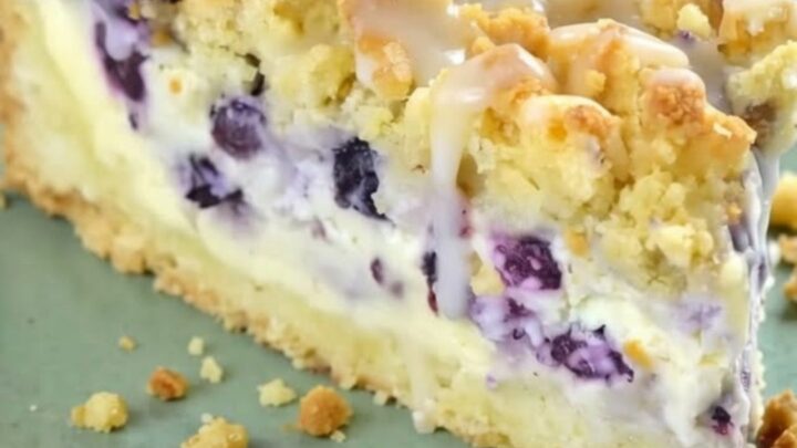 A golden-brown blueberry cheesecake crumb cake topped with almond crumble and a sweet white glaze drizzle.