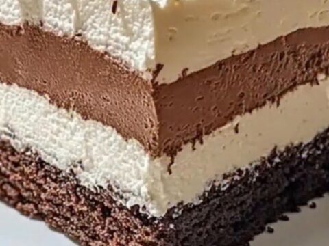 Gâteau trois chocolats avec des couches distinctes, surmonté de copeaux de chocolat noir.