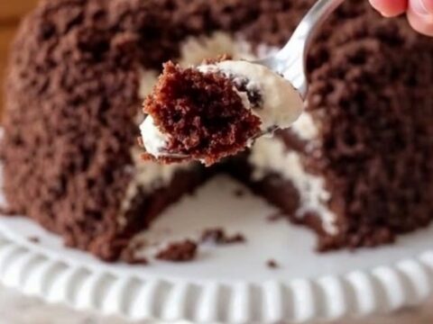 Gâteau crumble au chocolat et crème coco présenté sur un plat sur pied blanc festonné.