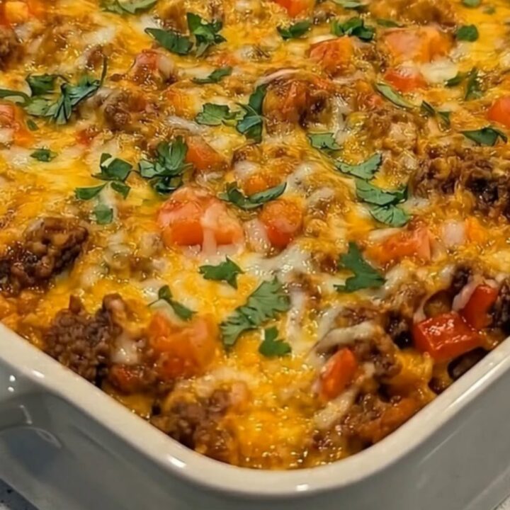 A freshly baked Beefy Fiesta Tortilla Casserole in a white baking dish, topped with bubbling melted cheese