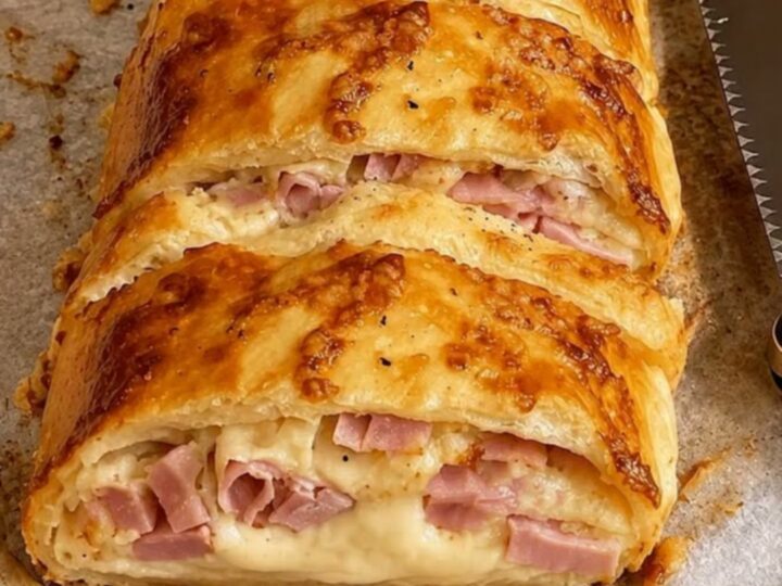Roulé croustillant doré au four, tranché pour montrer le fromage fondu et le jambon.
