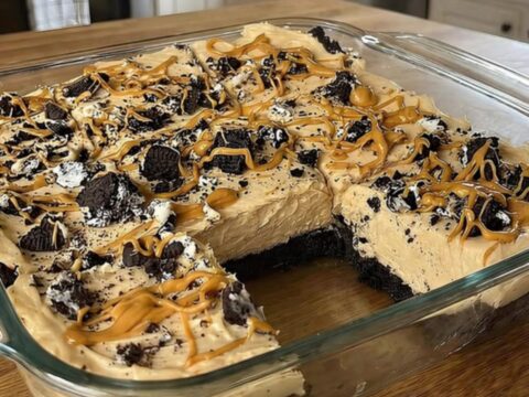 A slice of no-bake peanut butter Oreo pie on a white plate with a dark cookie crust.