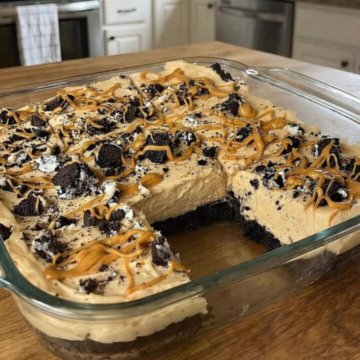 A slice of no-bake peanut butter Oreo pie on a white plate with a dark cookie crust.