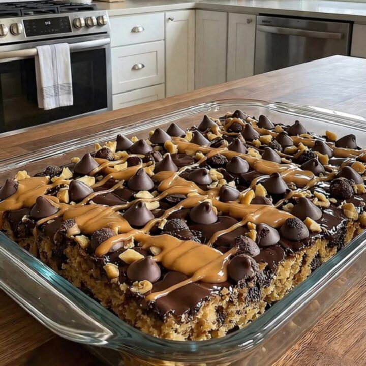 Gâteau fondant au chocolat et beurre de cacahuète dans son plat en verre, garni de pépites et de cacahuètes.