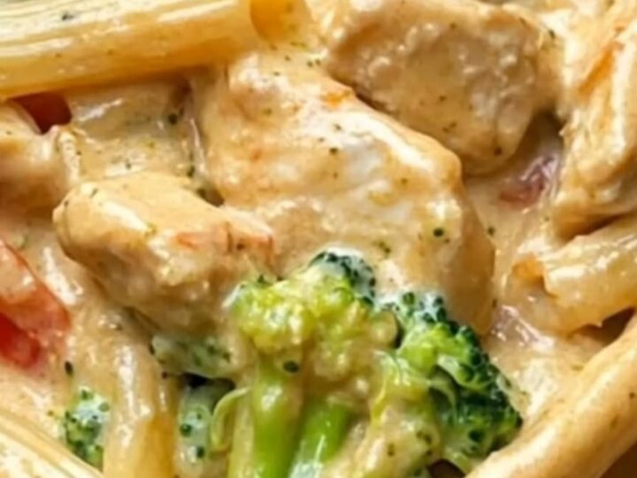 A close-up of a creamy chicken and broccoli penne pasta dish in a skillet with a rich cheese pull.