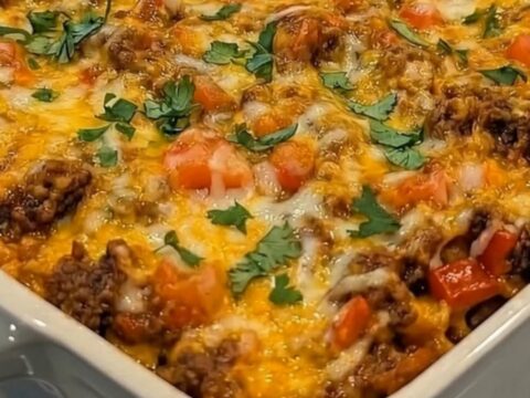 A warm slice of Beef Fiesta Tortilla Casserole being lifted with a long, gooey cheese pull.