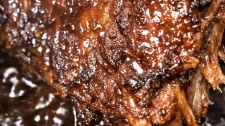 A rack of tender cola-glazed ribs resting on a white plate with visible juices.