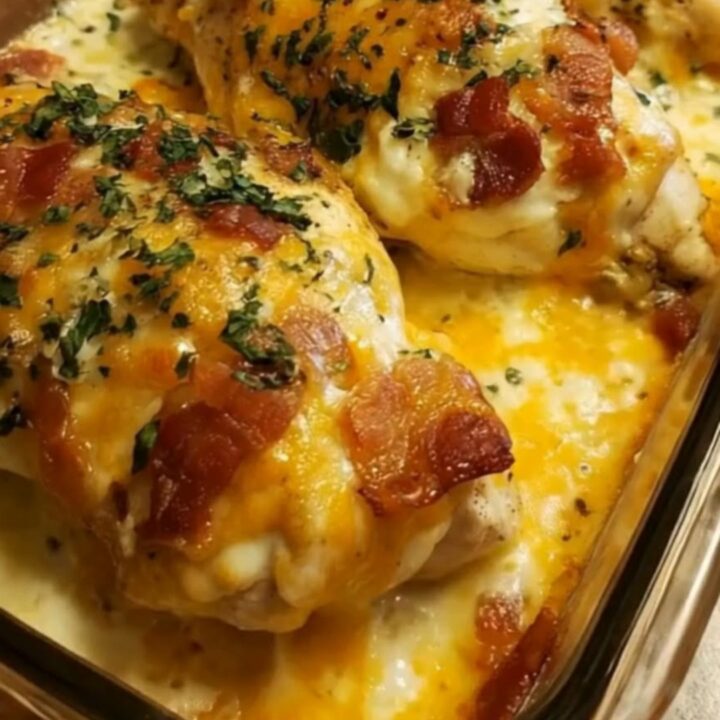 A golden, baked chicken breast topped with melted cheddar and mozzarella cheese, crispy bacon
