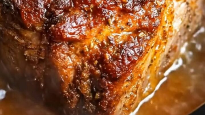 A succulent maple mustard pork roast served on a white plate with a glossy glaze.
