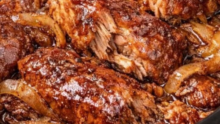 A close-up of tender, saucy country-style ribs in a slow cooker with caramelized onions.