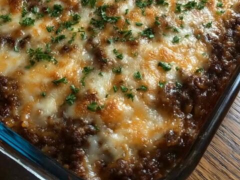 A steaming, cheesy French onion beef and rice casserole in a glass baking dish.