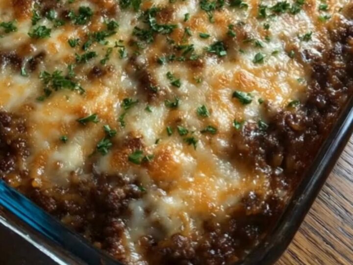 A steaming, cheesy French onion beef and rice casserole in a glass baking dish.