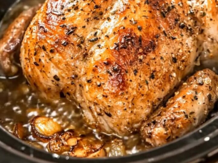 A golden-brown whole roasted chicken steaming inside a slow cooker, looking tender and juicy.