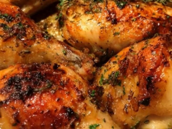 Golden-brown roasted chicken drumsticks arranged neatly in a metal roasting pan.