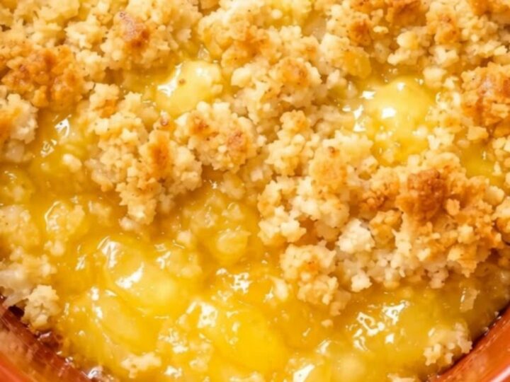 A warm scoop of slow cooker lemon dump cake with a golden crispy crumble topping and bubbling yellow filling