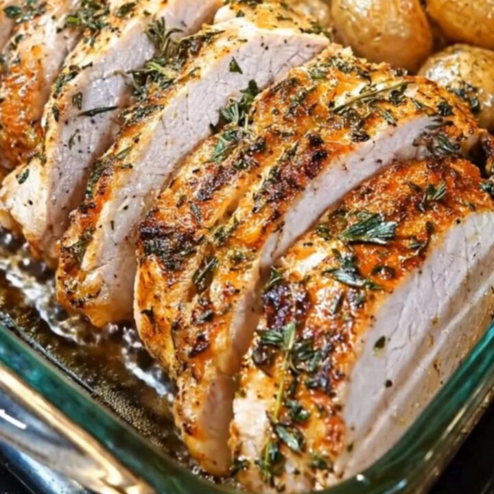A clear glass baking dish containing roasted chicken breast, golden potatoes, and green beans.
