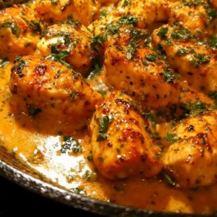 Golden seared chicken bites in a cast-iron skillet, topped with fresh parsley and a rich garlic butter sauce.