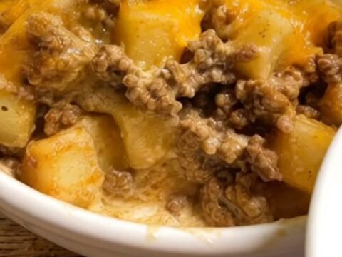 A white bowl filled with creamy taco seasoned ground beef, tender potatoes, and gooey melted cheddar cheese.