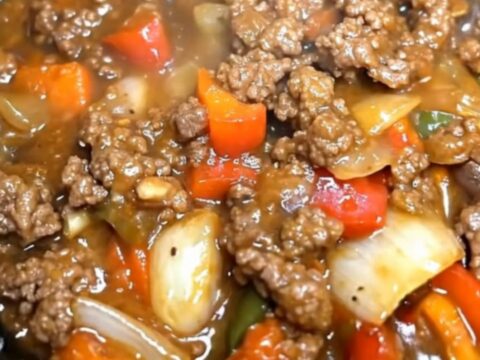 A hearty serving of slow cooker pepper steak with vibrant bell peppers and rich gravy in a black slow cooker.