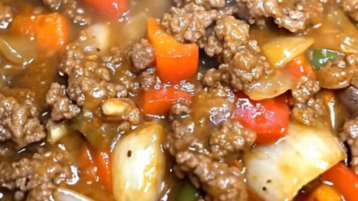 A hearty serving of slow cooker pepper steak with vibrant bell peppers and rich gravy in a black slow cooker.