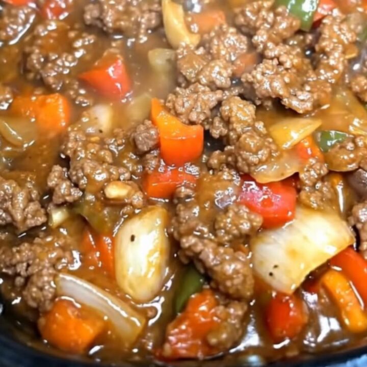 A hearty serving of slow cooker pepper steak with vibrant bell peppers and rich gravy in a black slow cooker.
