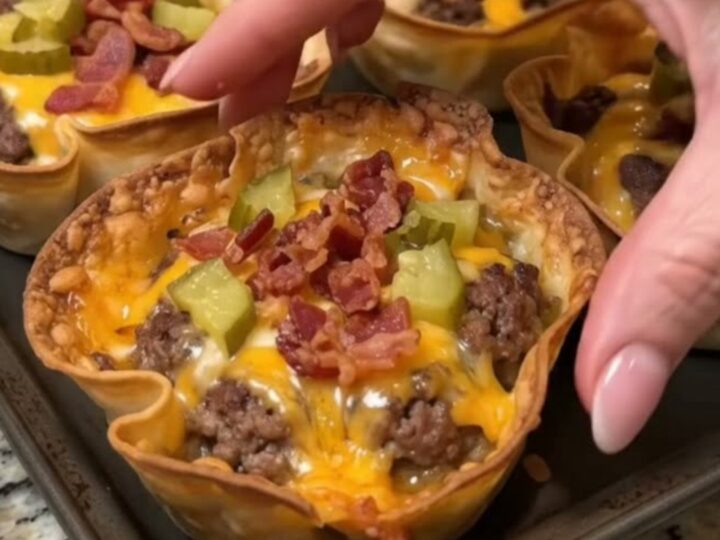 A platter of crispy golden tortilla cups filled with seasoned ground beef, melted cheddar cheese, bacon, and pickles.